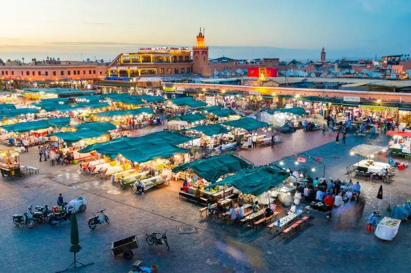 Evening market scene in Marrakesh, Morocco, showcasing vibrant stalls and warm, inviting lights: Morrocon Guided Tour